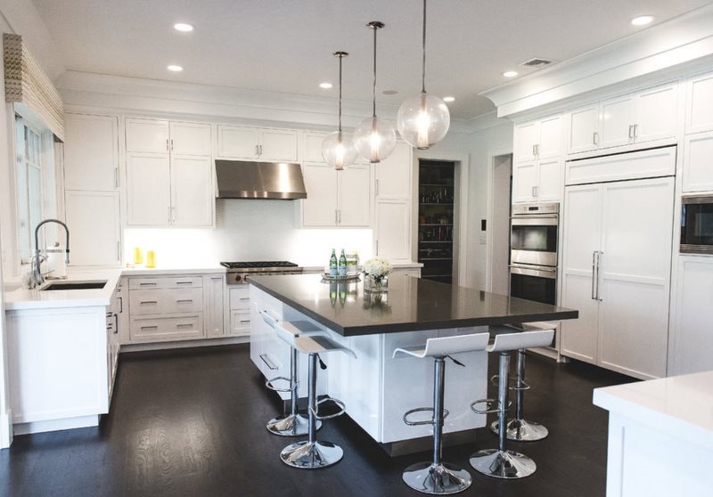 Mutfak adasının siyah yüzeyi ve beyaz mobilyalar