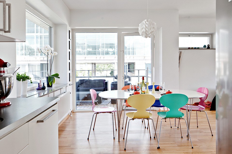 Chairs of different colors in the kitchen with white walls