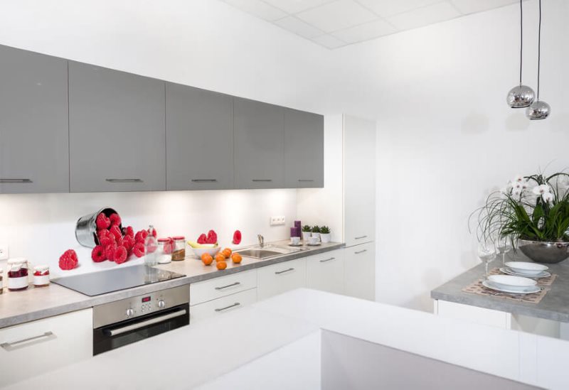 Armarios colgantes grises sobre un delantal de vidrio de cocina