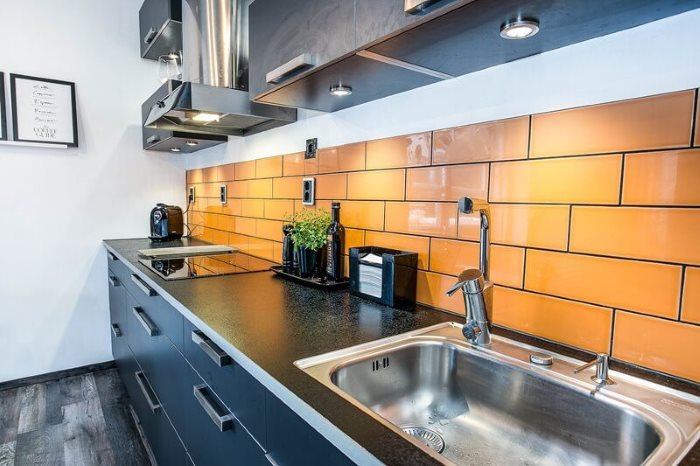 Azulejo naranja en el delantal de una cocina lineal