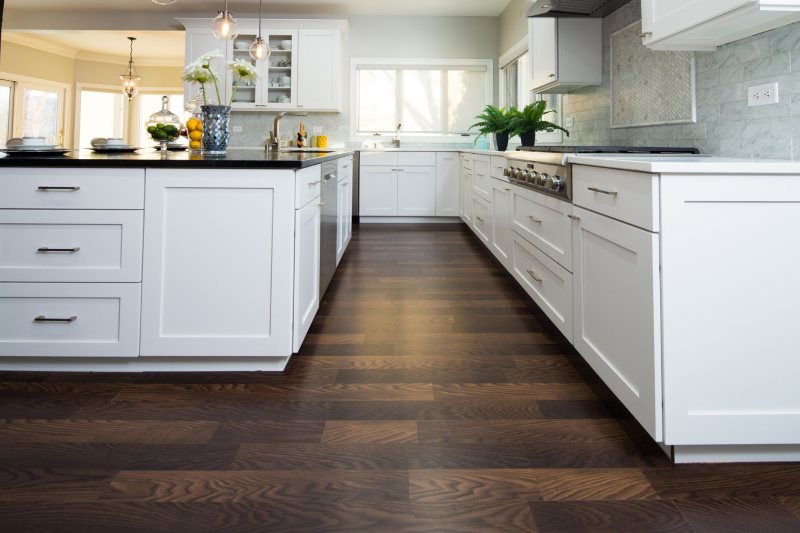 Piso de madera color chocolate en la cocina con muebles blancos.
