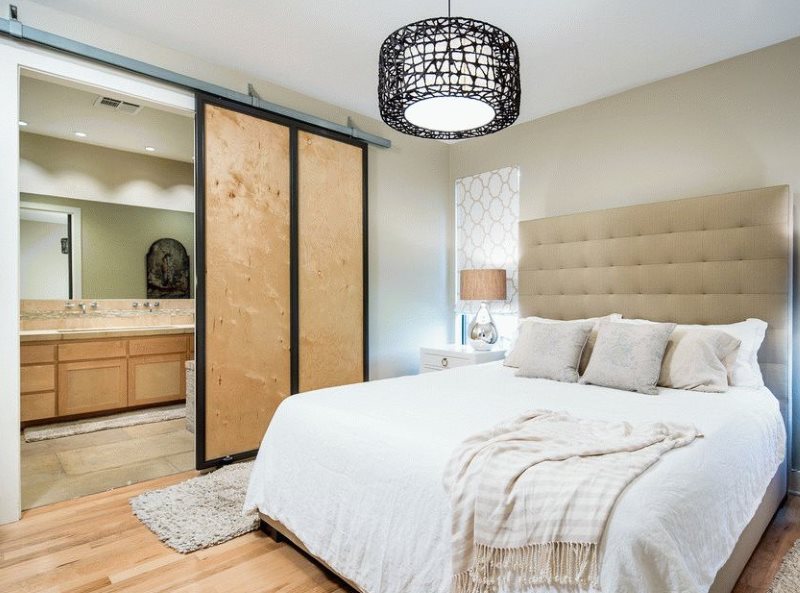 Puertas correderas de madera contrachapada entre el dormitorio y el baño.