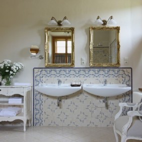 Deux miroirs dans des cadres dorés dans une salle de bain combinée