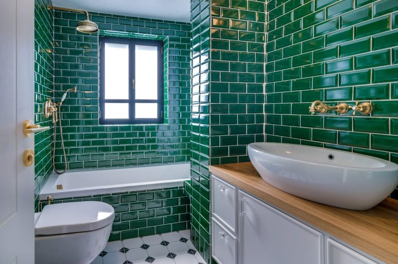 Emerald color tiles on the walls of the bathroom with a window