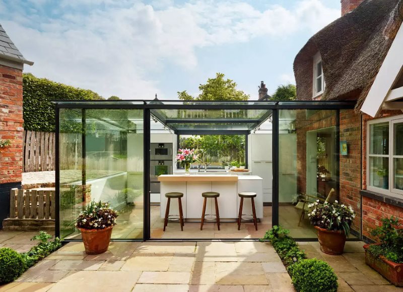 Γυάλινη καλοκαιρινή κουζίνα στην αυλή ενός εξοχικού σπιτιού