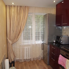 Réfrigérateur près de la fenêtre avec un rideau asymétrique